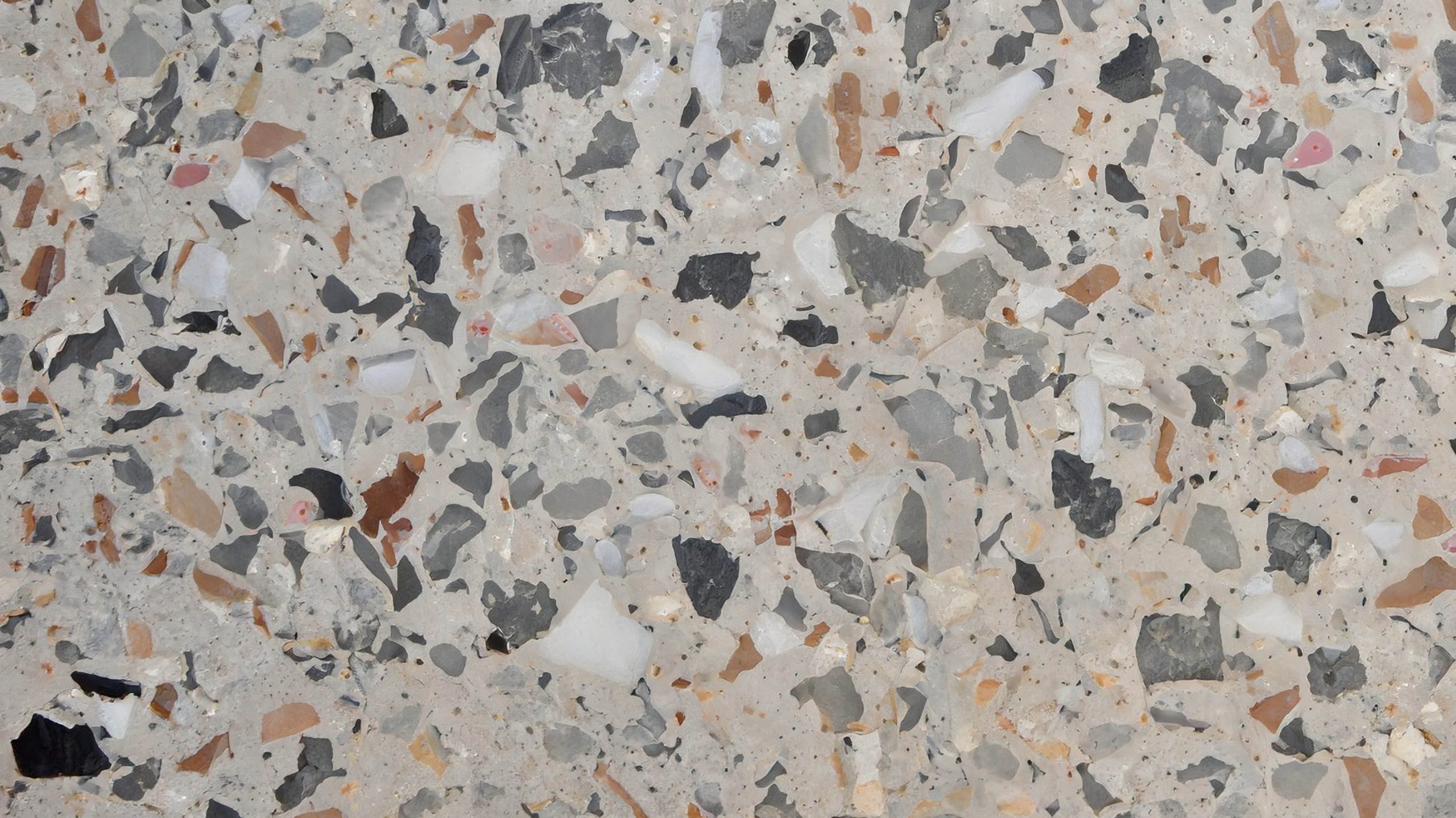 grijze doorsnede van beton waarbij verschillend toeslagmateriaal zichtbaar is